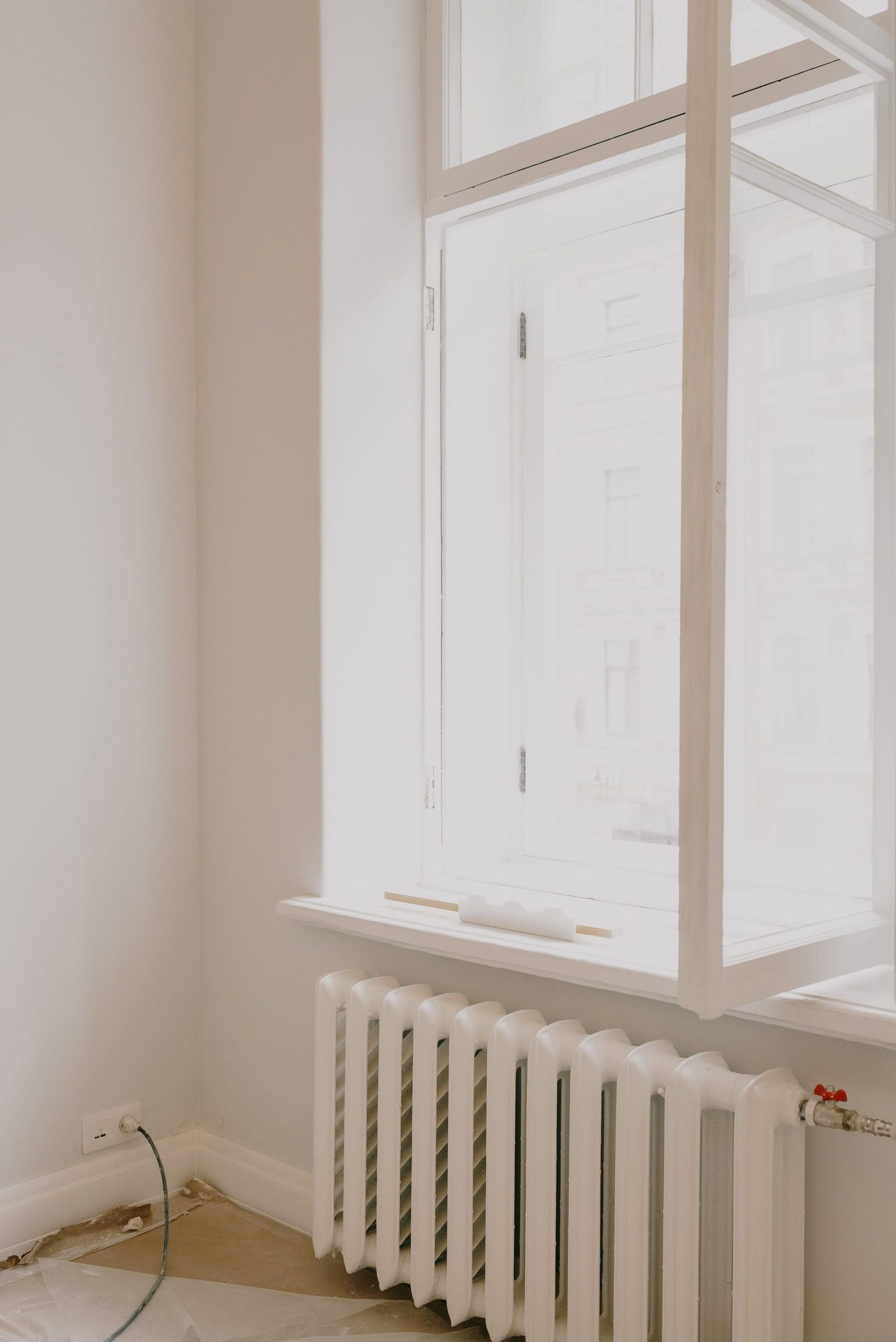 White column radiator beneath a bright window in a freshly decorated room