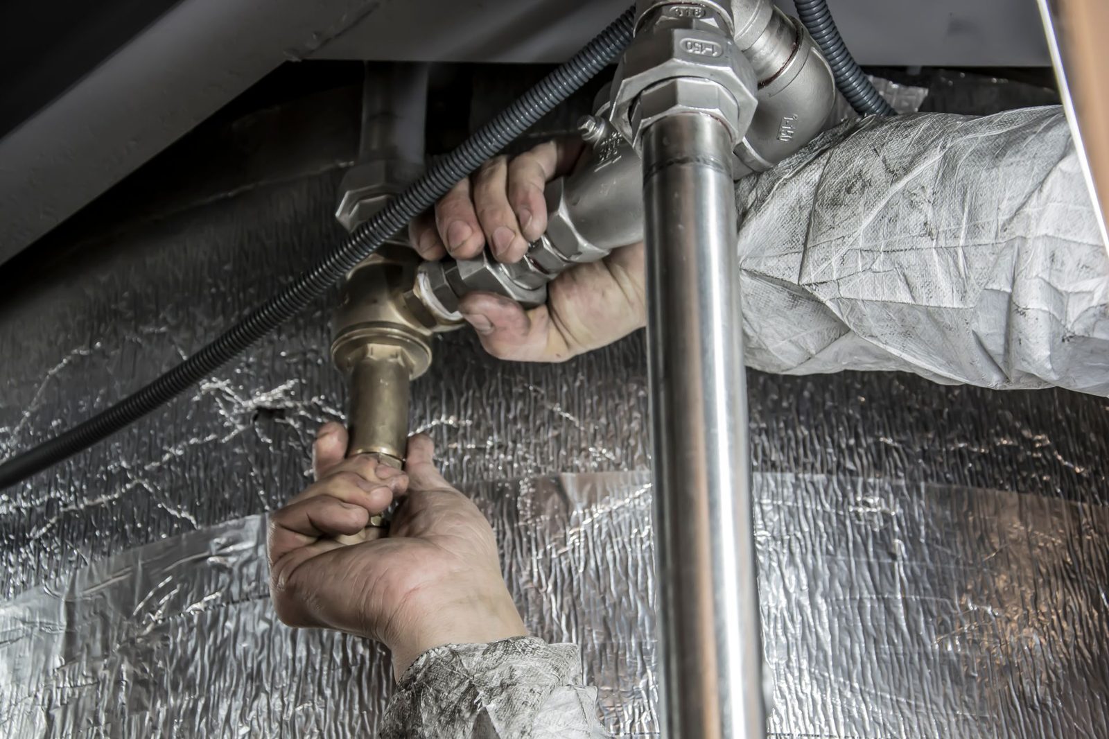 Hands tightening steel pipe fittings during a heating repair