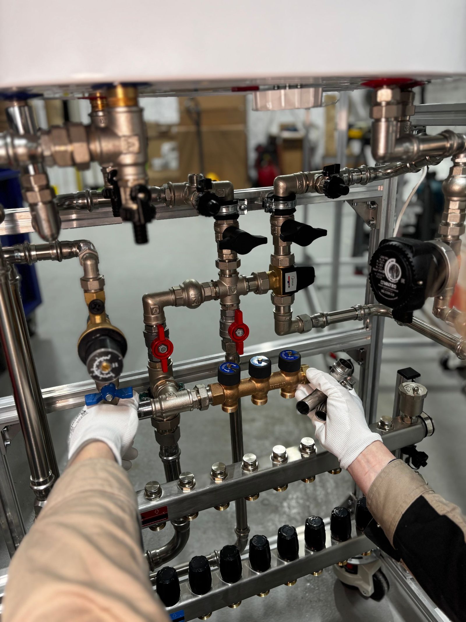 Gloved hands adjusting valves on a central heating manifold